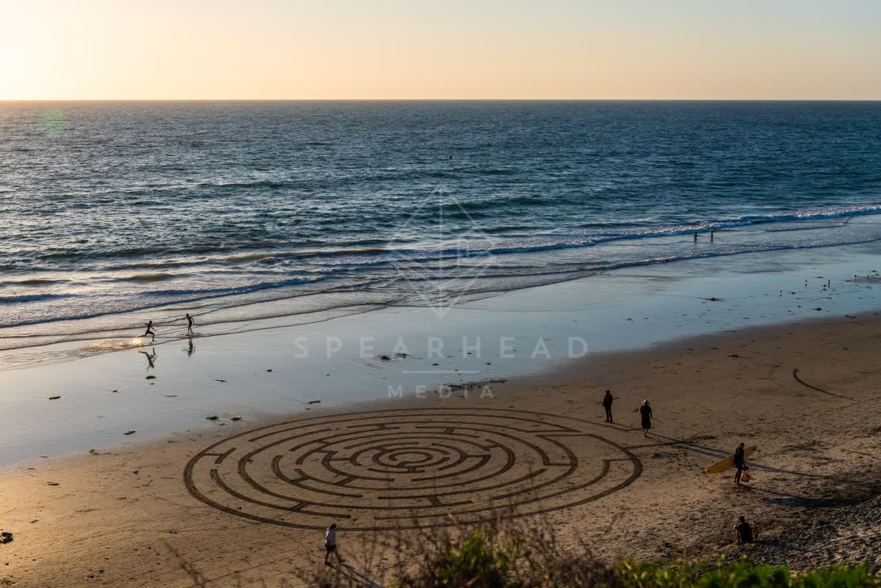 Elevated view of the beach, the surf and the ocean at Moonlight Beach, with people walking.