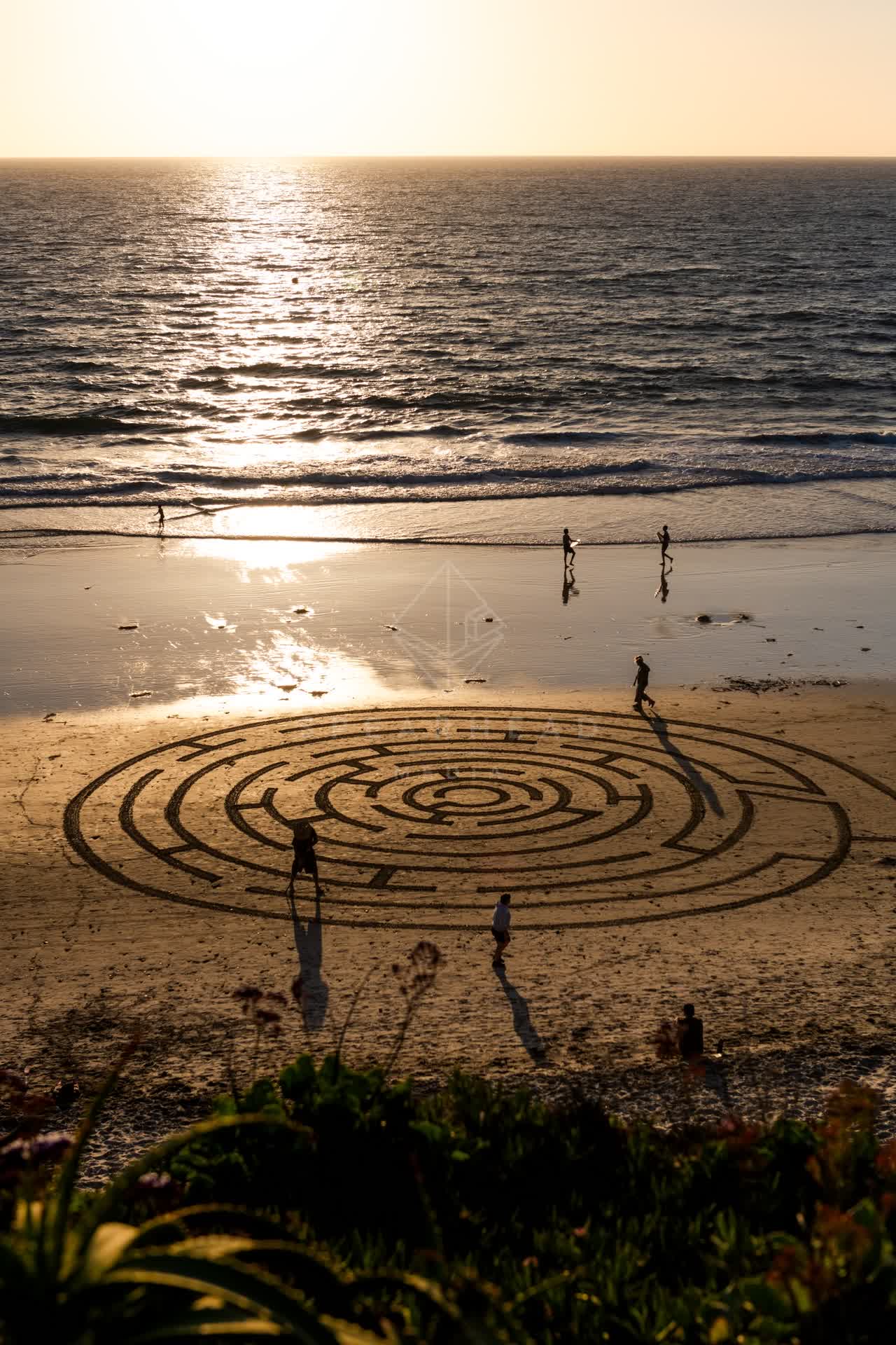 Elevated view of the beach, the surf and the ocean at Moonlight Beach, with people walking.