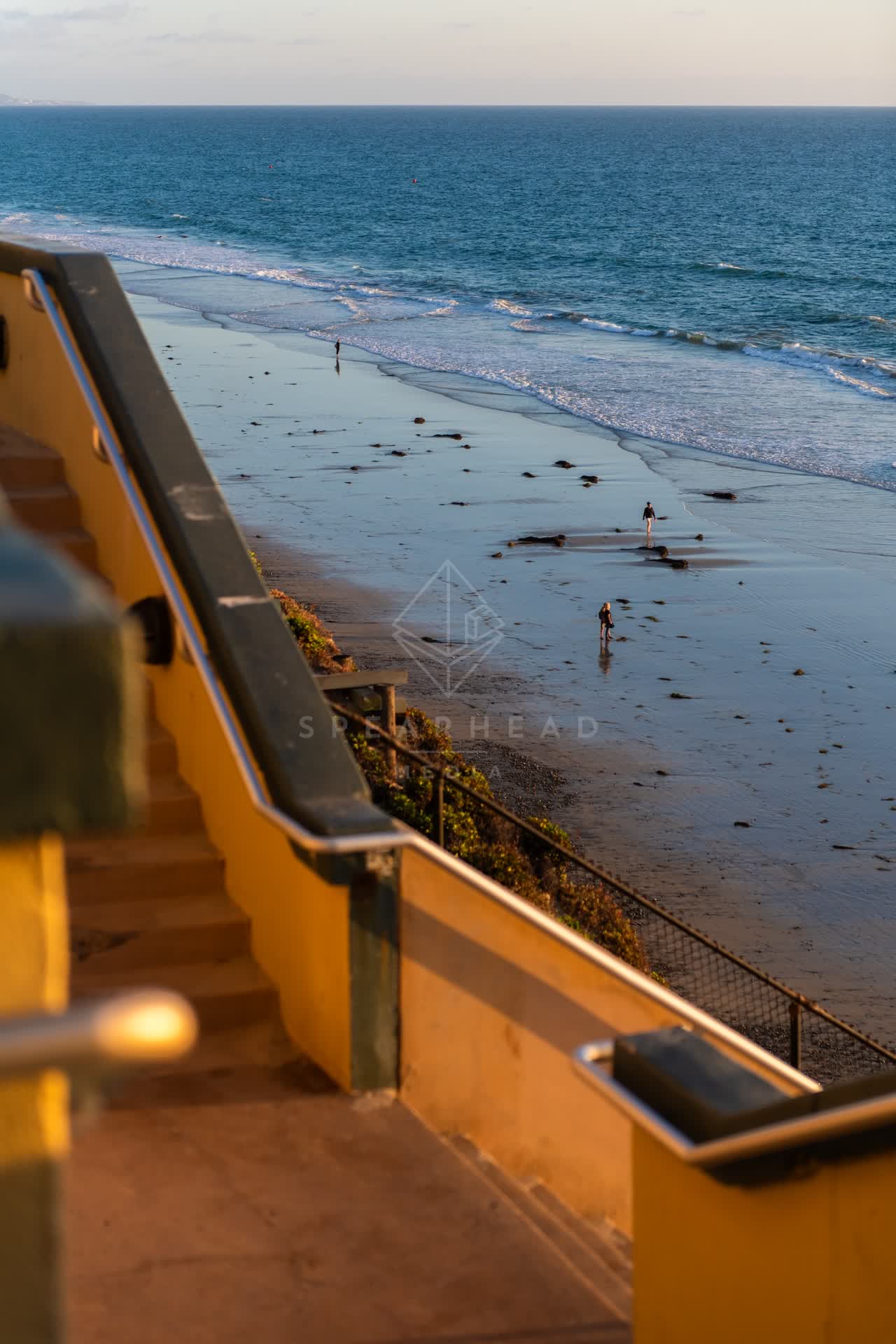Elevated view of the beach, the surf and the ocean in Encinitas, with people walking.