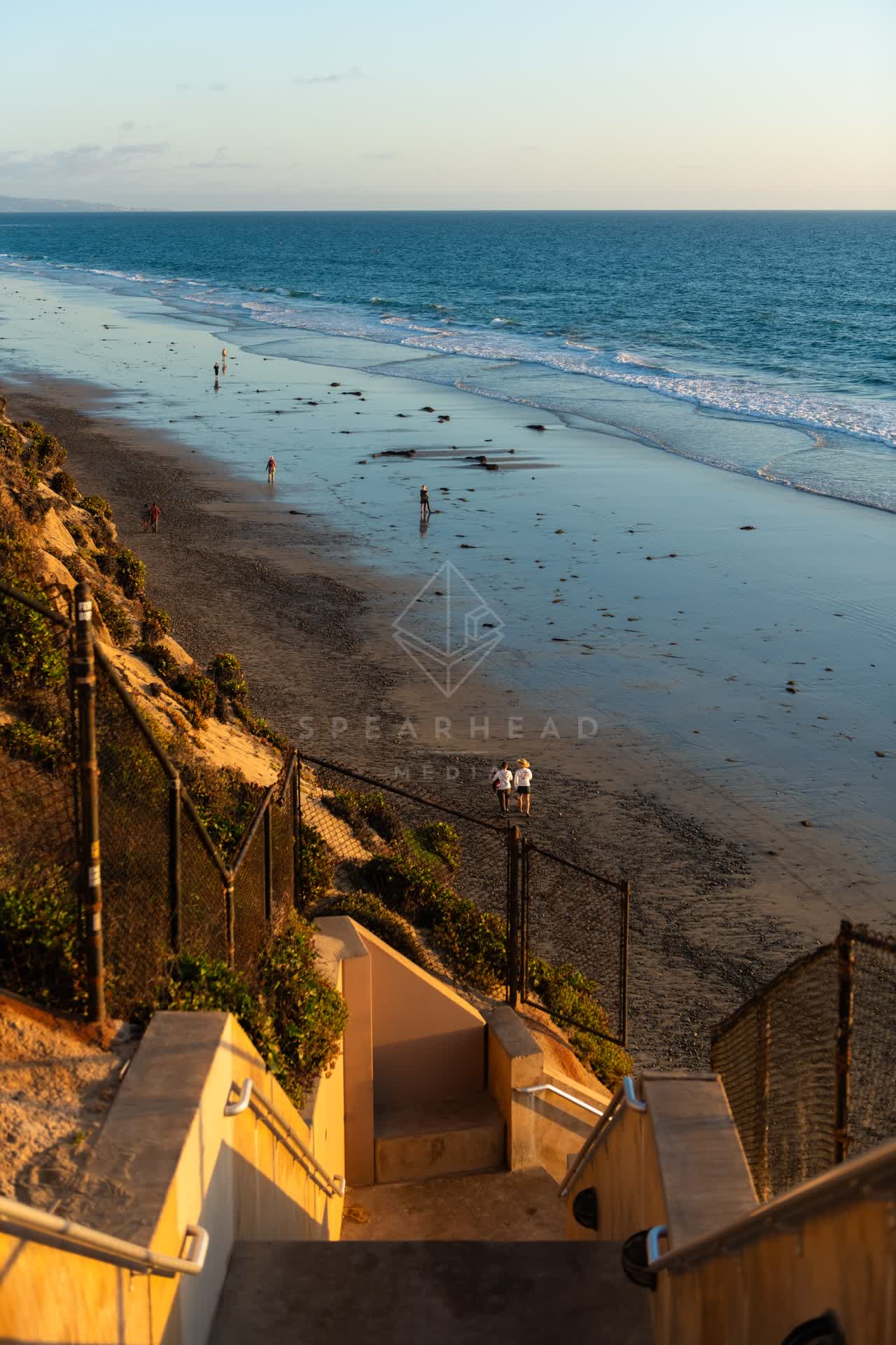 Elevated view of the beach, the surf and the ocean in Encinitas, with people walking.