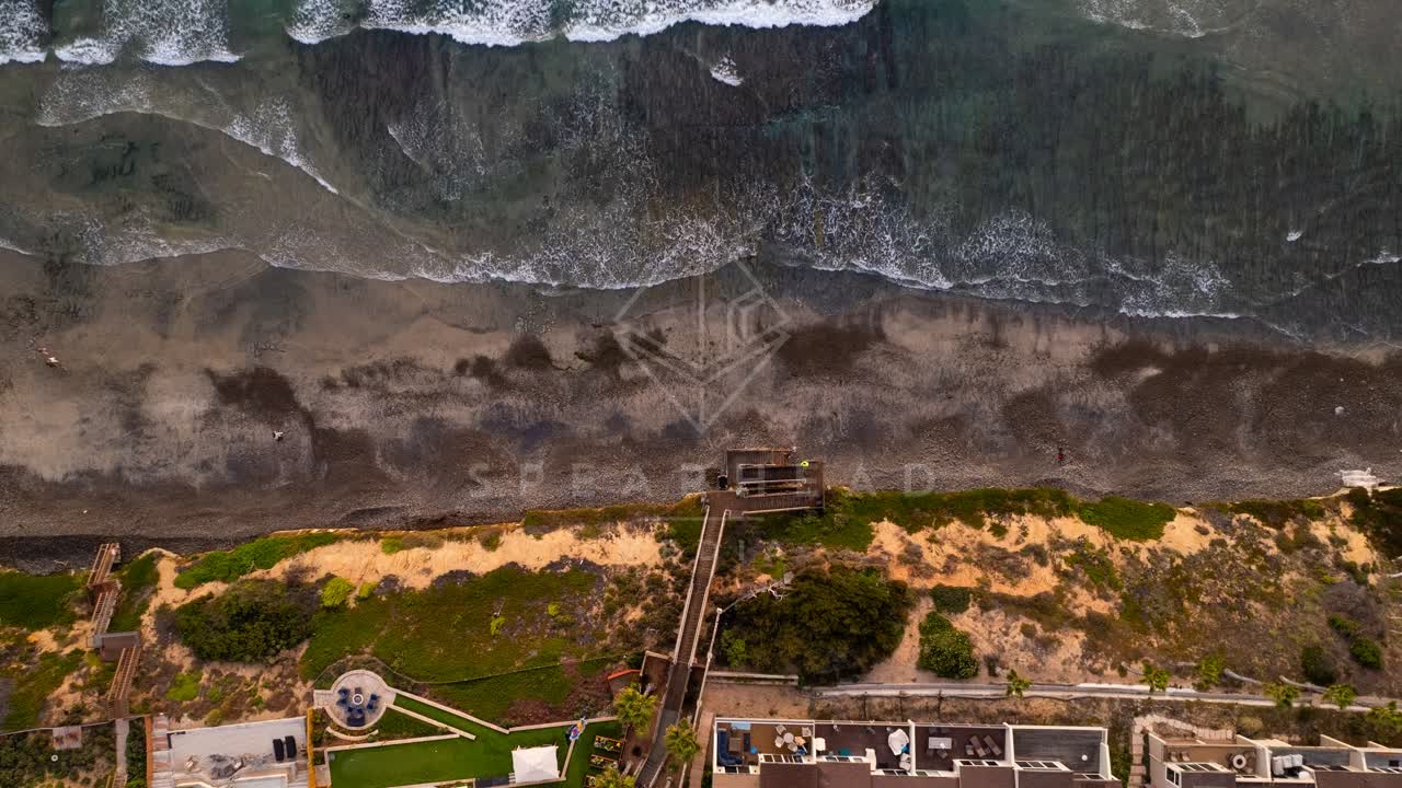 Aerial view of the beach, the surf and the ocean in Encinitas, with people walking.