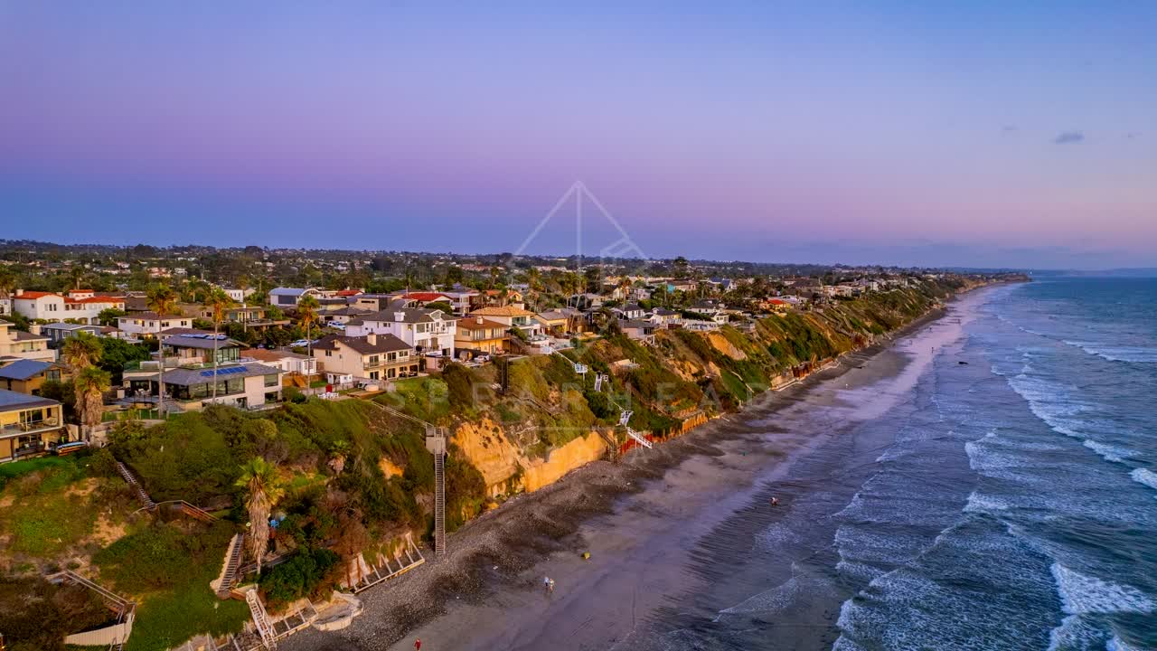 Aerial view of the cliffs, palm trees and the ocean in Encinitas, with people walking.
