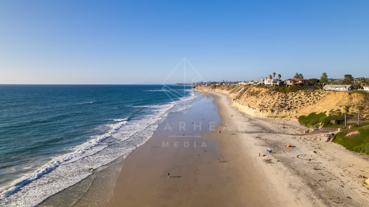 Aerial view of the beach, the surf and palm trees at Fletcher Cove, with people walking.
