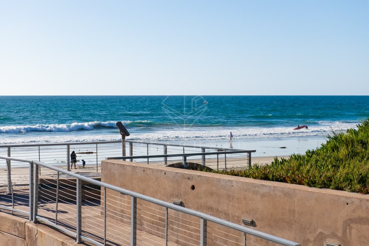 Elevated view of the beach, the surf and the ocean at Fletcher Cove, with people walking.