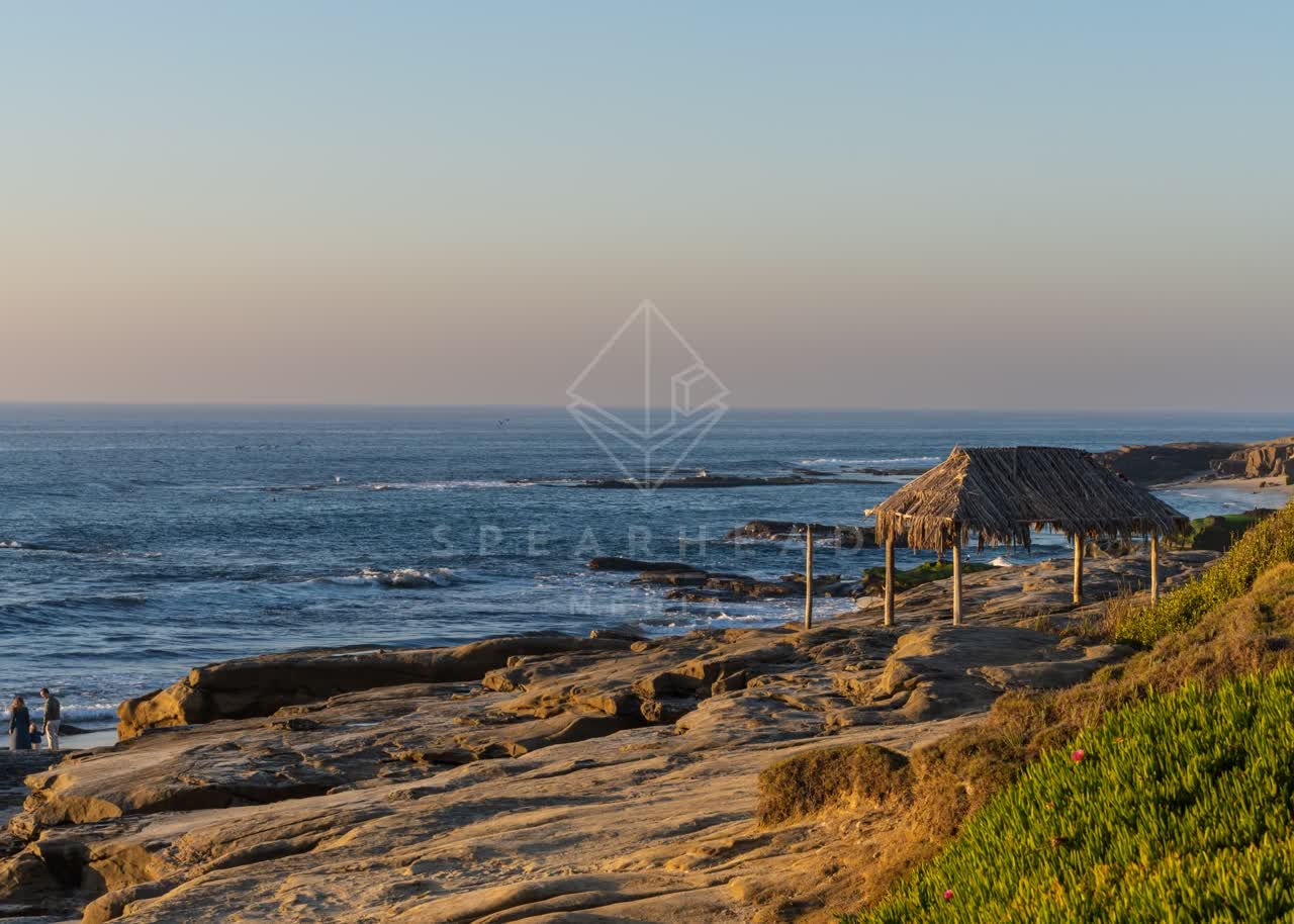 Elevated view of the cliffs, the ocean and open country at Windansea, with people walking.