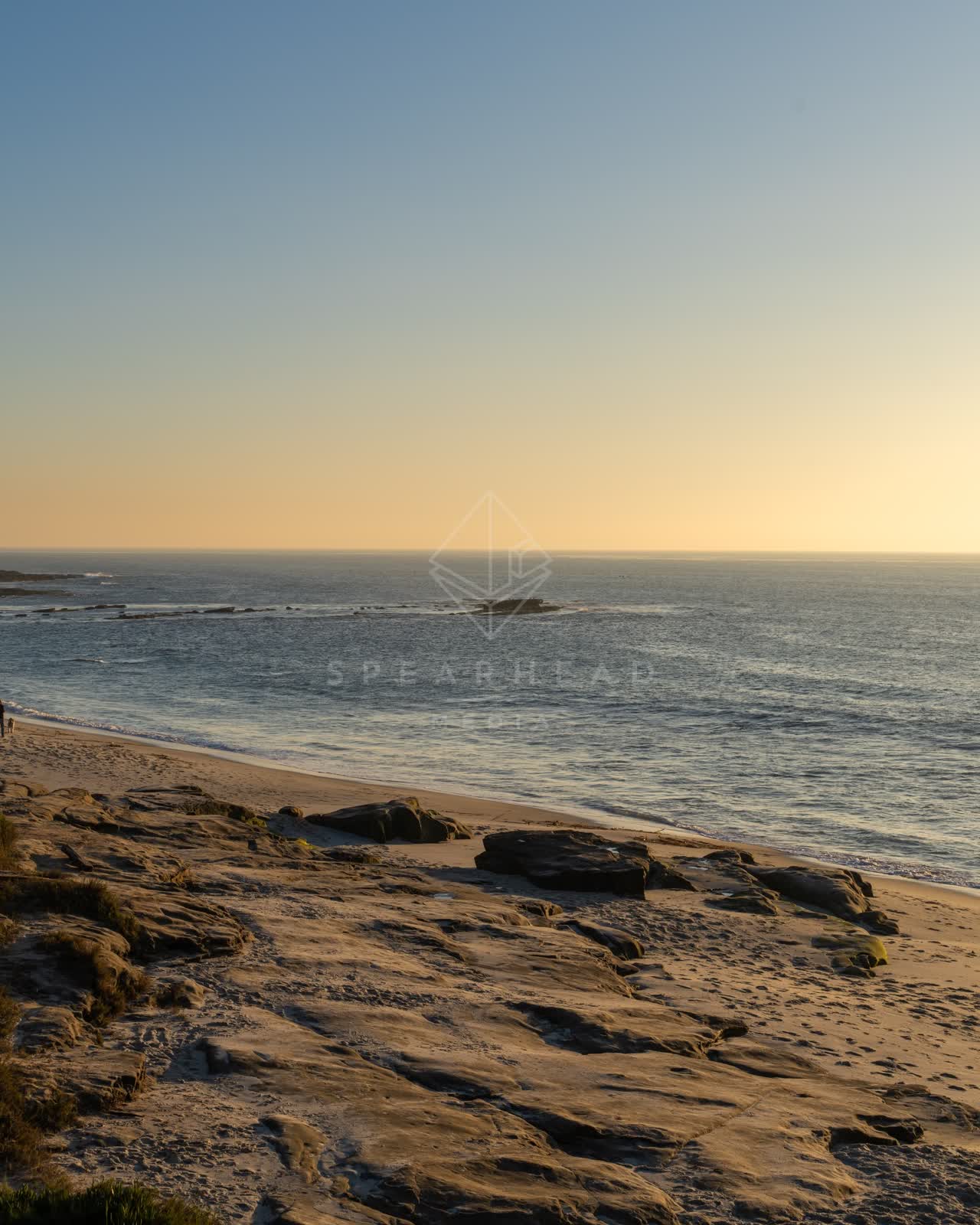 Elevated view of the beach, the surf and the ocean at Windansea, with people walking.