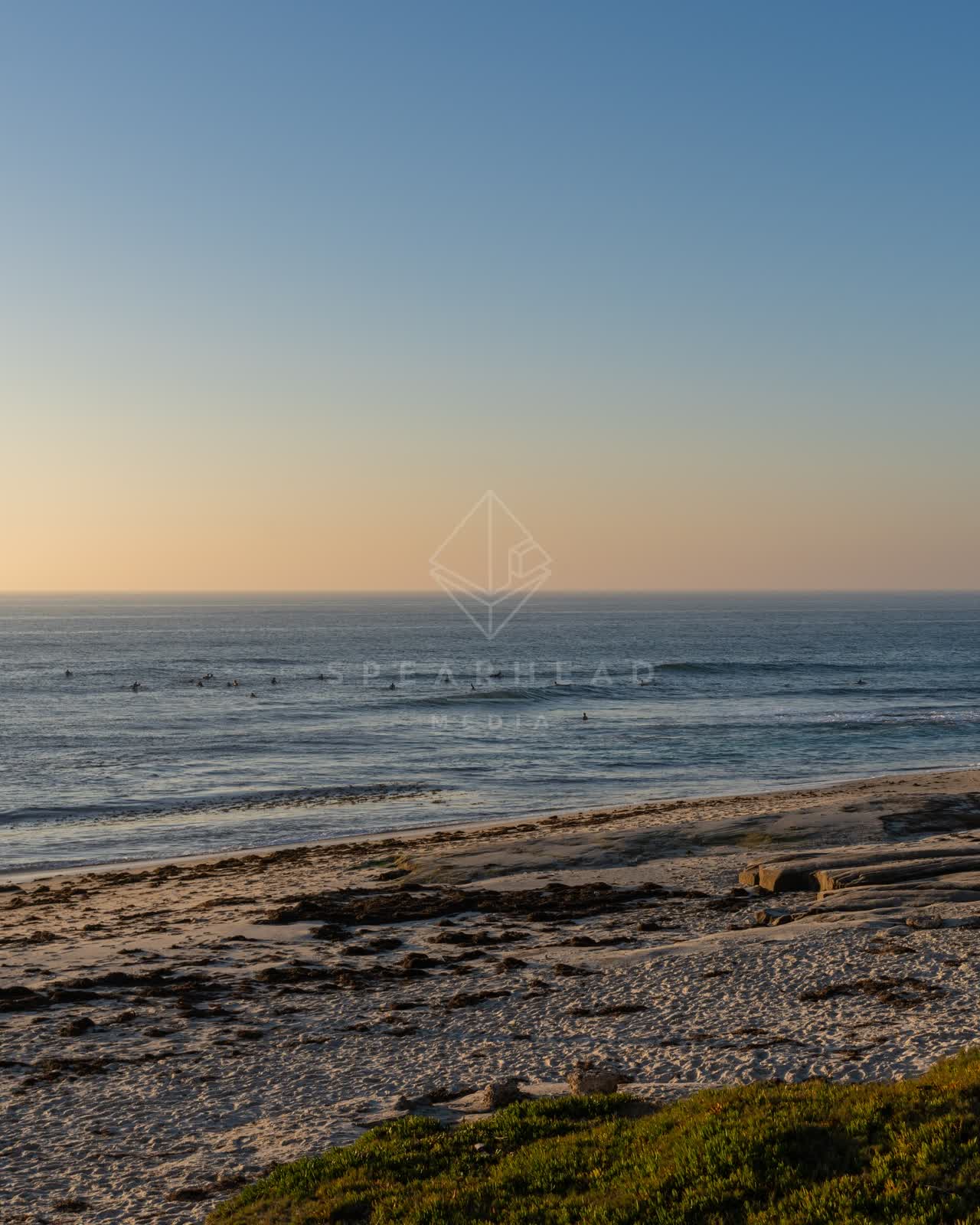 Elevated view of the beach, the surf and the ocean at Windansea, with surfers out.