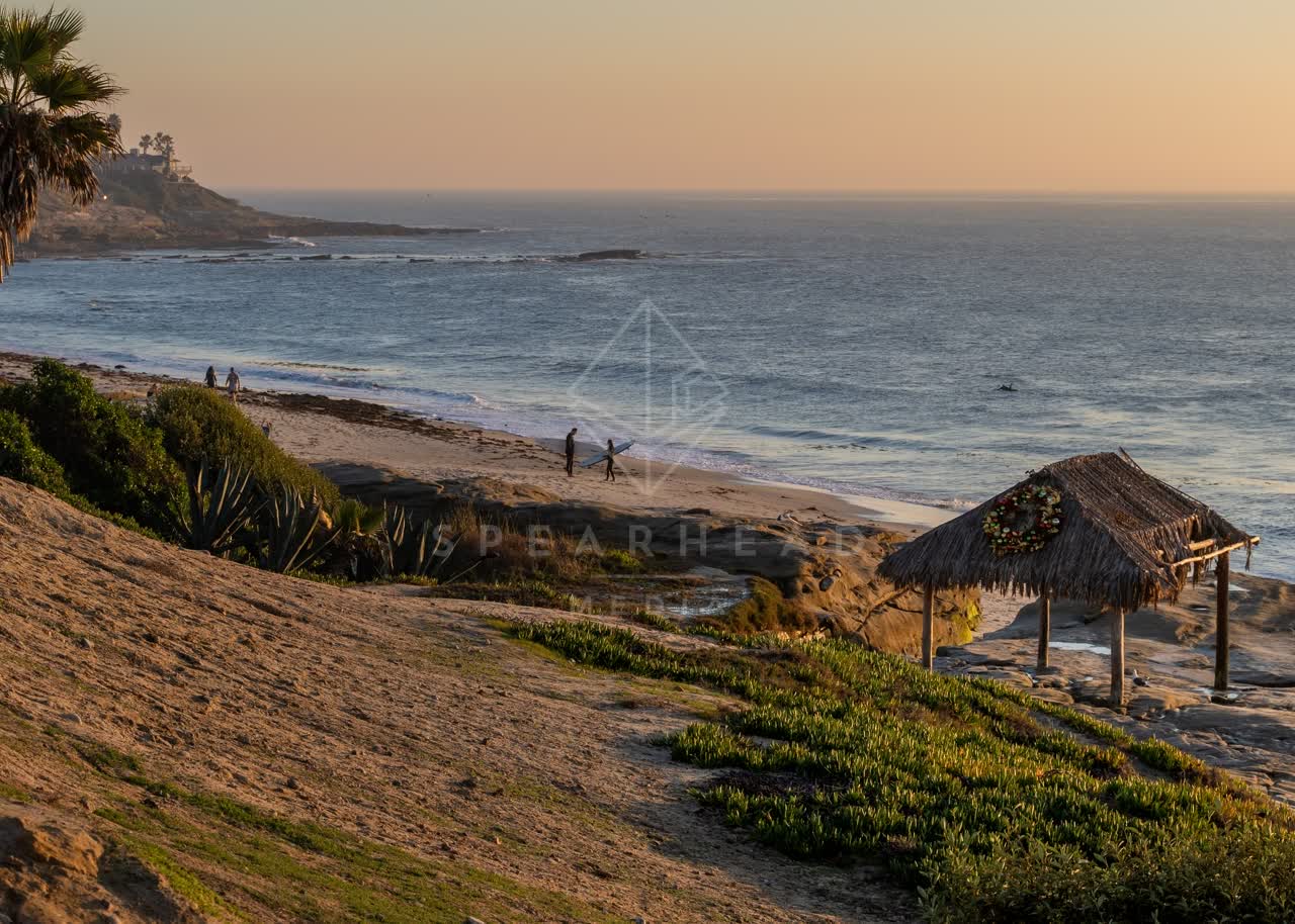 Elevated view of the cliffs, the surf and the ocean at Windansea, with people walking.