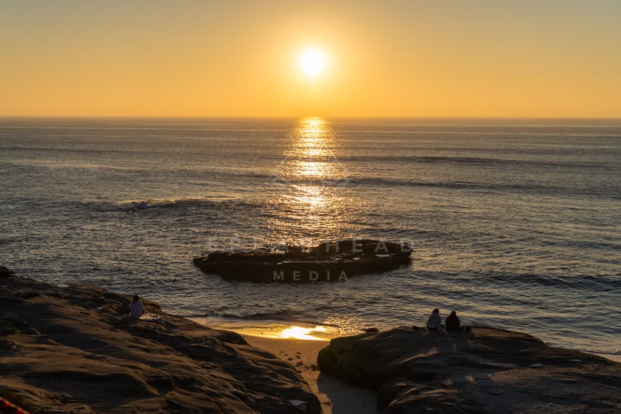 Elevated view of the cliffs, the ocean and the beach at Windansea, with people walking.