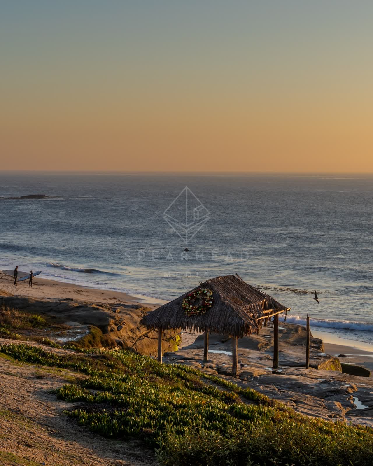 Elevated view of the cliffs, the surf and the ocean at Windansea, with people walking.