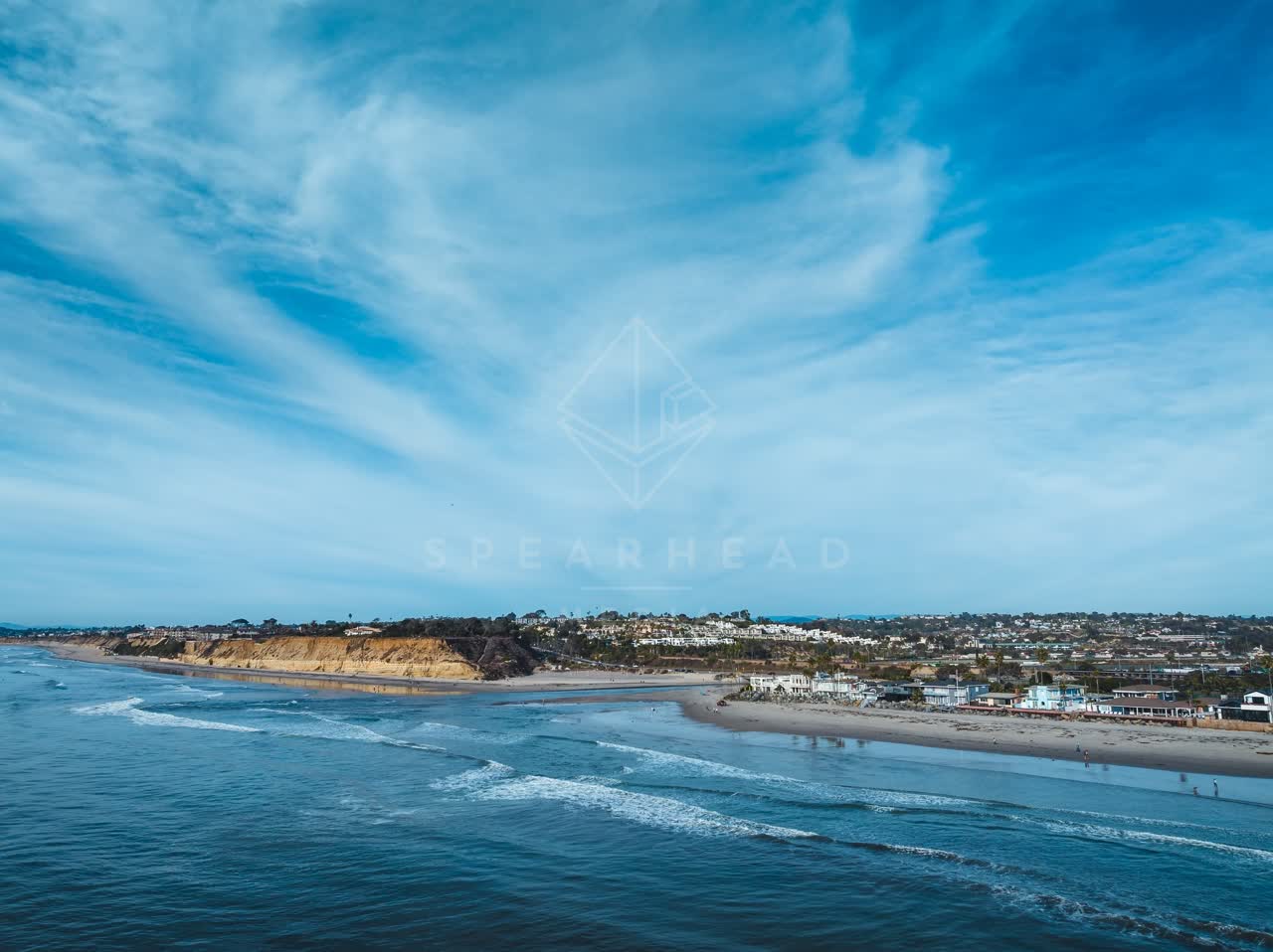 Aerial view of the beach, the ocean and homes at Del Mar Dog Beach, with people walking.
