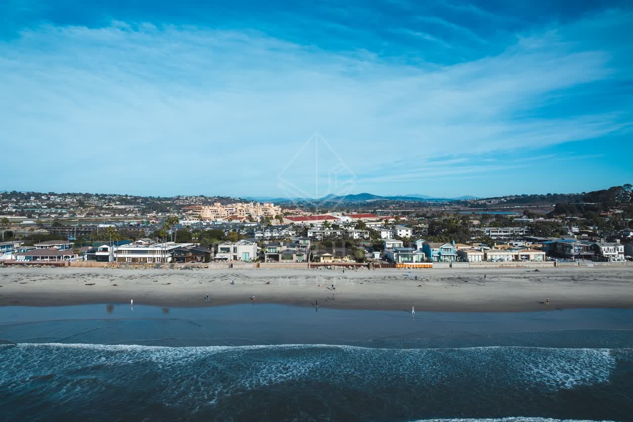 Aerial view of the beach, the surf and the ocean at Del Mar Dog Beach, with people walking.