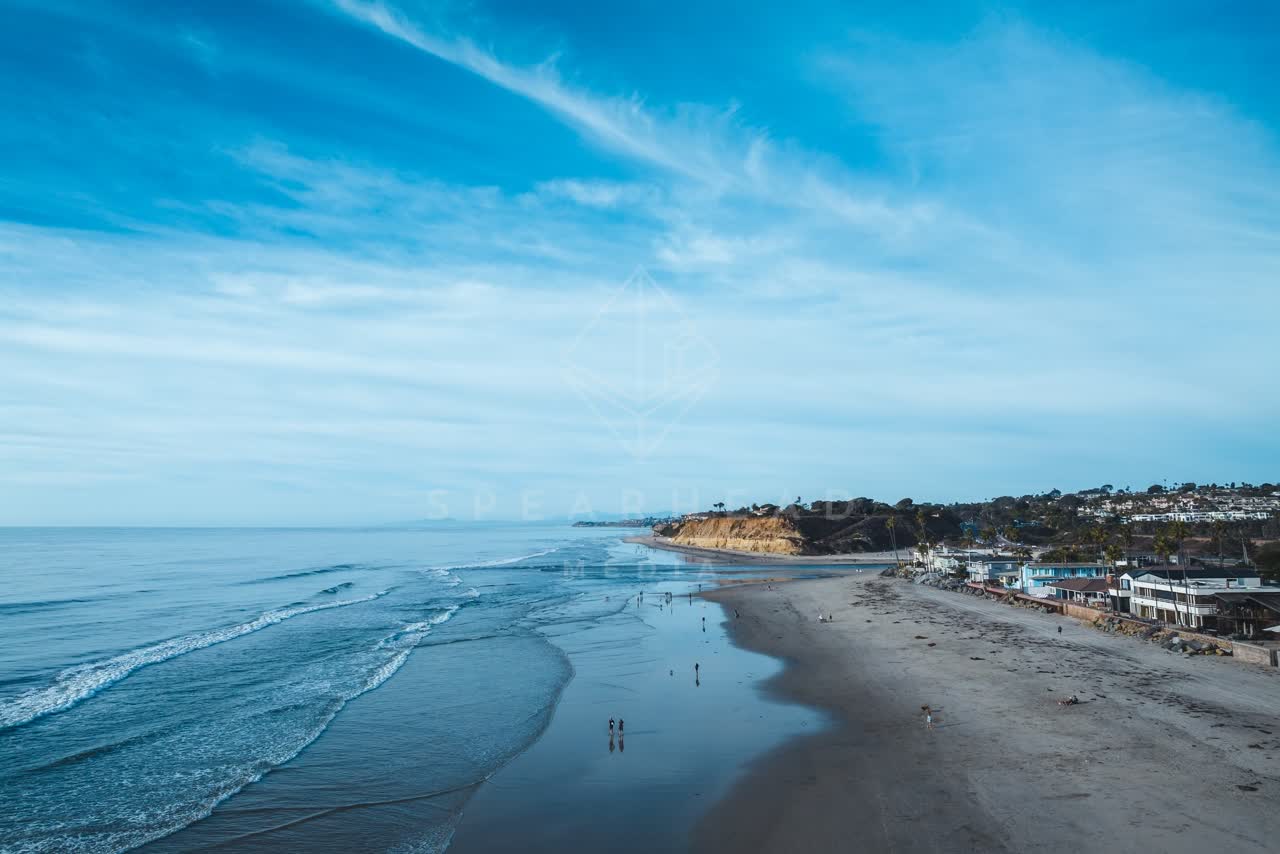 Aerial view of the beach, the ocean and homes at Del Mar Dog Beach, with people walking.