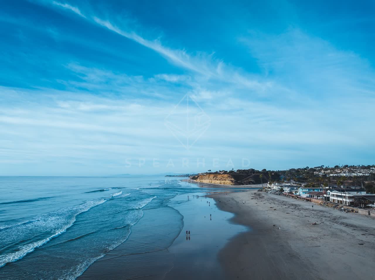 Aerial view of the beach, the ocean and homes at Del Mar Dog Beach, with people walking.