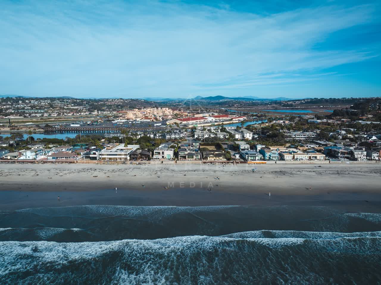 Aerial view of the beach, the surf and the ocean at Del Mar Dog Beach, with people walking.