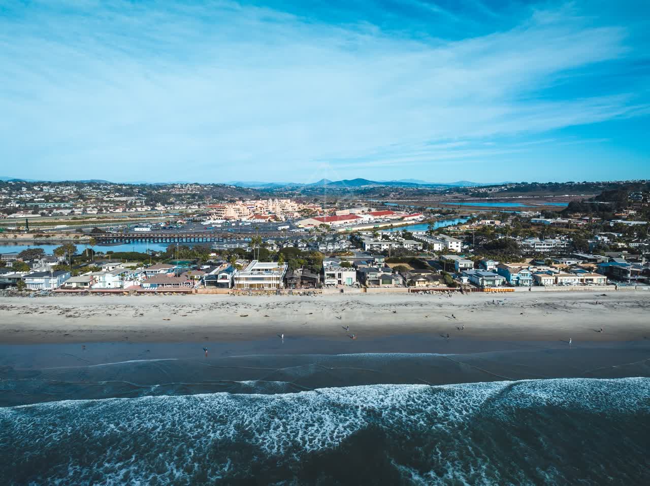 Aerial view of the beach, the surf and the ocean at Del Mar Dog Beach, with people walking.