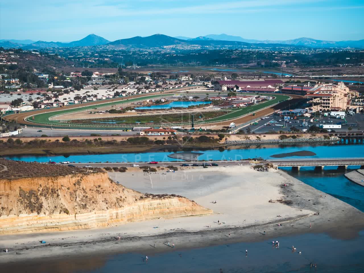 Aerial view of the beach, the bridge and the ocean at Del Mar Dog Beach, with people walking.