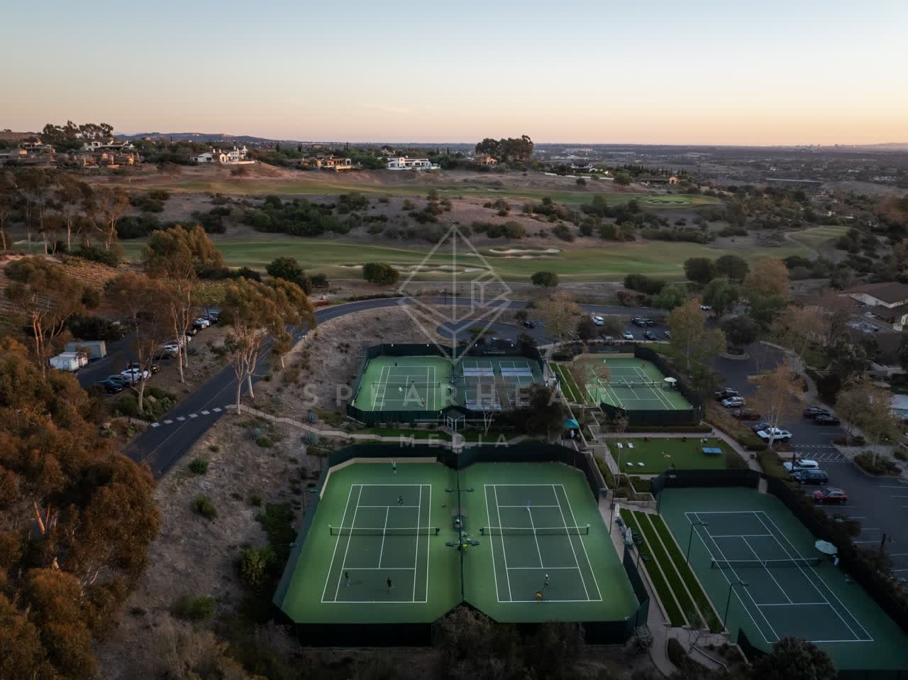 Aerial view of the country inland, homes and traffic in Santaluz, with swimmers in the water.