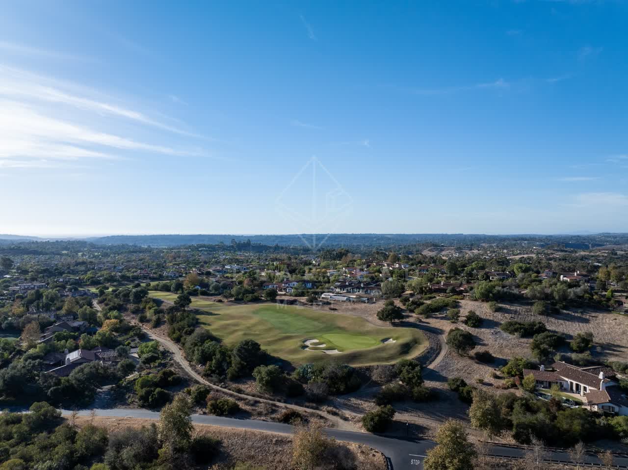 Aerial view of a residential street, homes and open country in Santaluz.