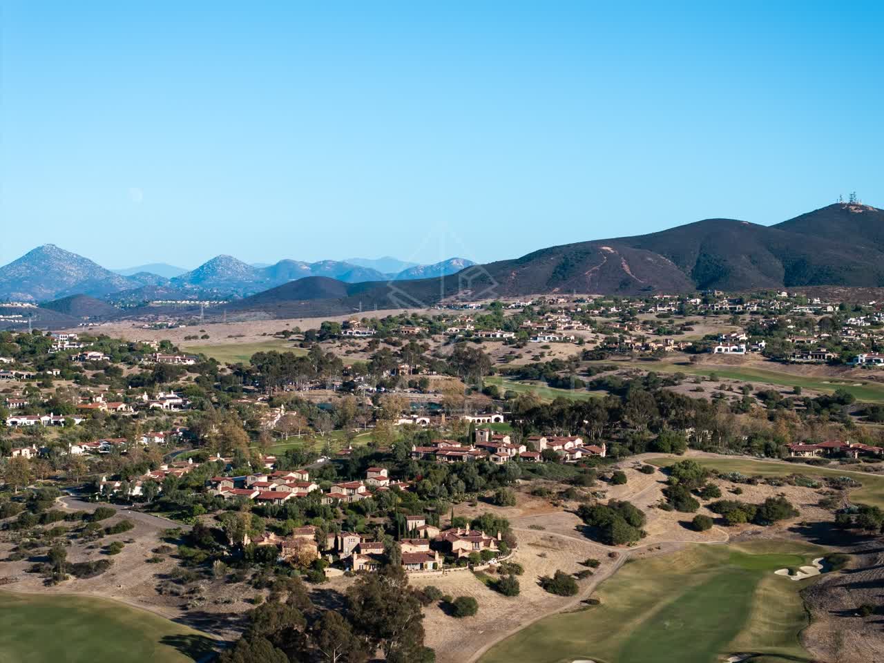 Aerial view of a residential street, homes and open country in Santaluz.