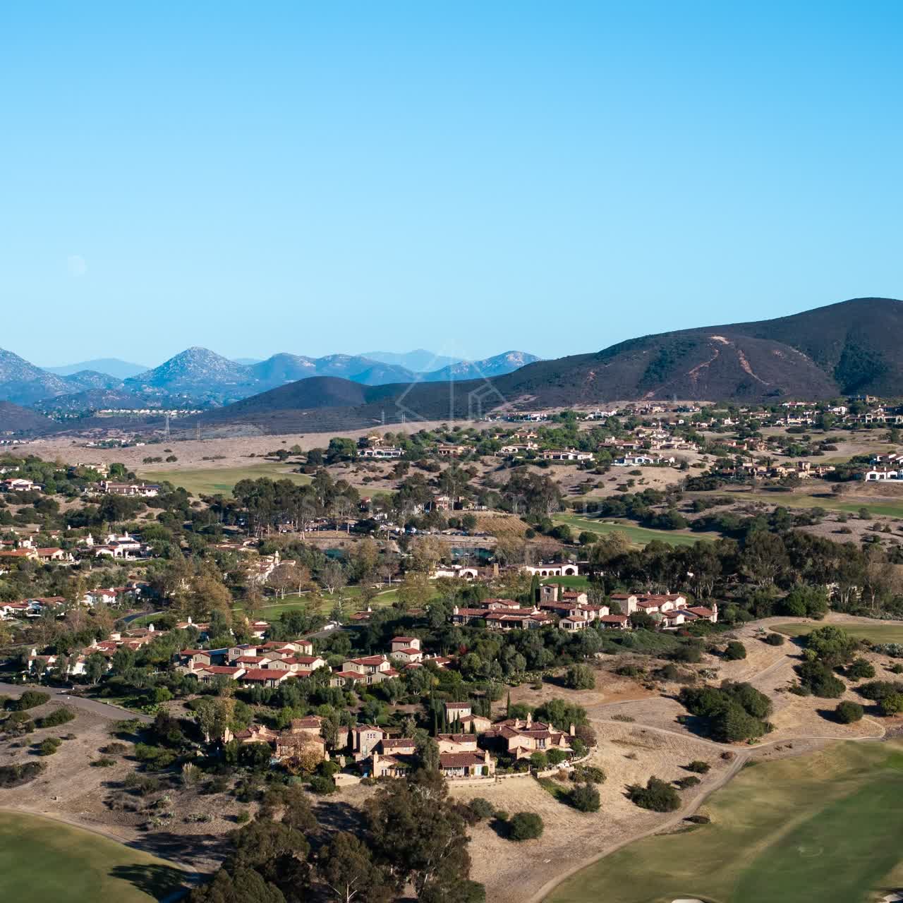 Aerial view of a residential street, homes and open country in Santaluz.