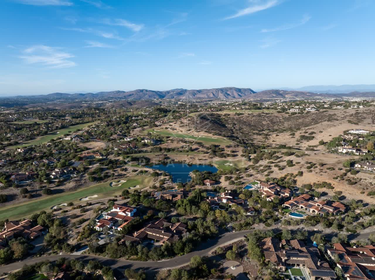 Aerial view of a residential street, homes and open country in Santaluz.