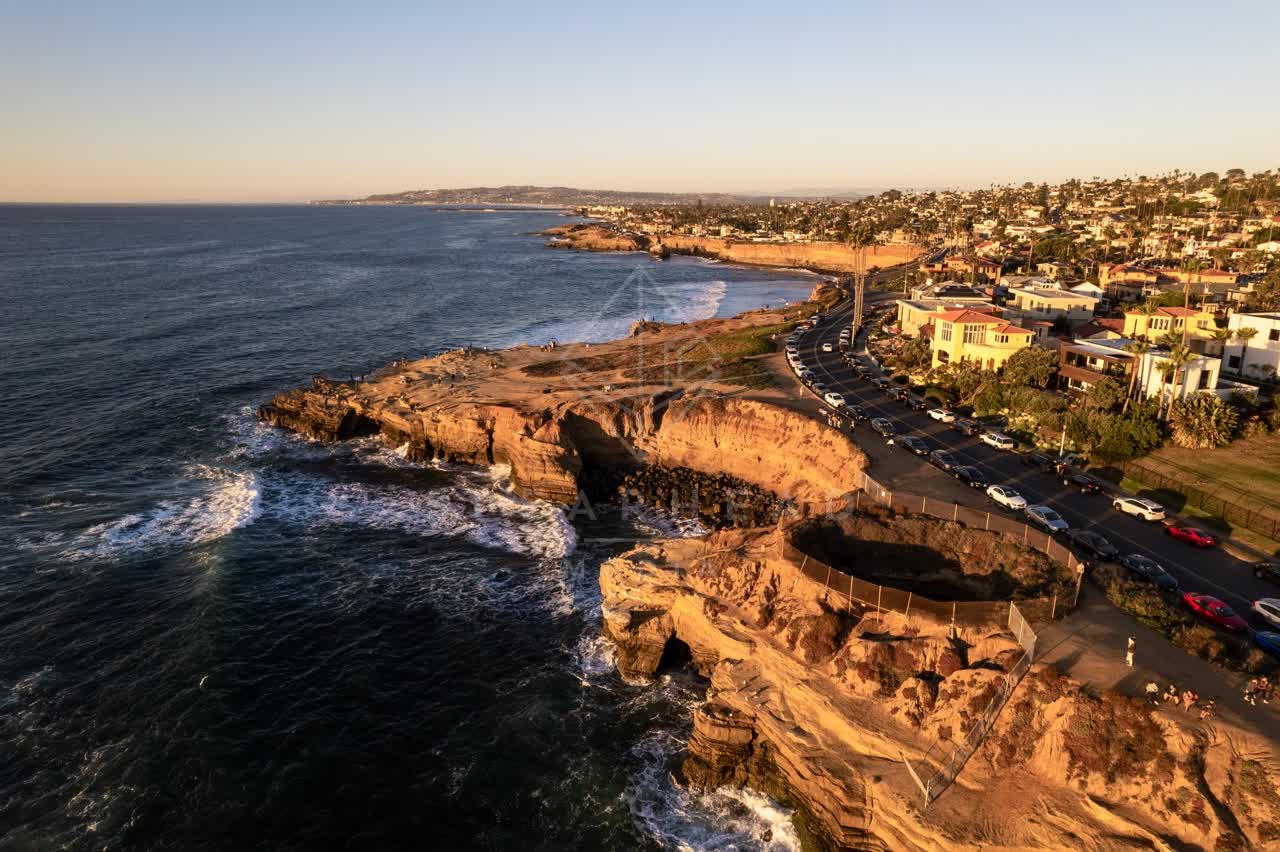 Aerial view of the cliffs, the surf and palm trees at Sunset Cliffs, with people walking.