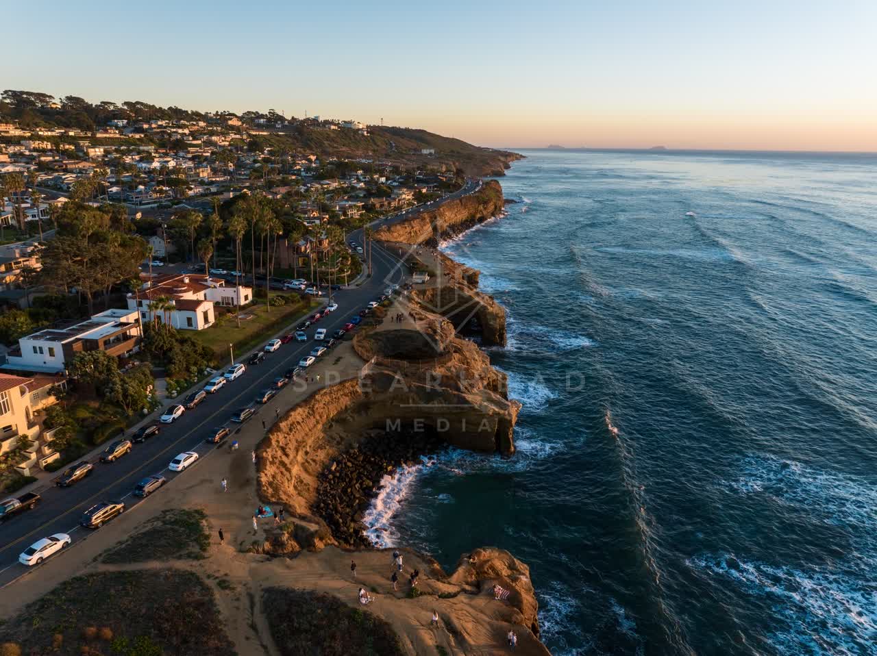 Aerial view of the cliffs, palm trees and the ocean at Sunset Cliffs, with people walking.