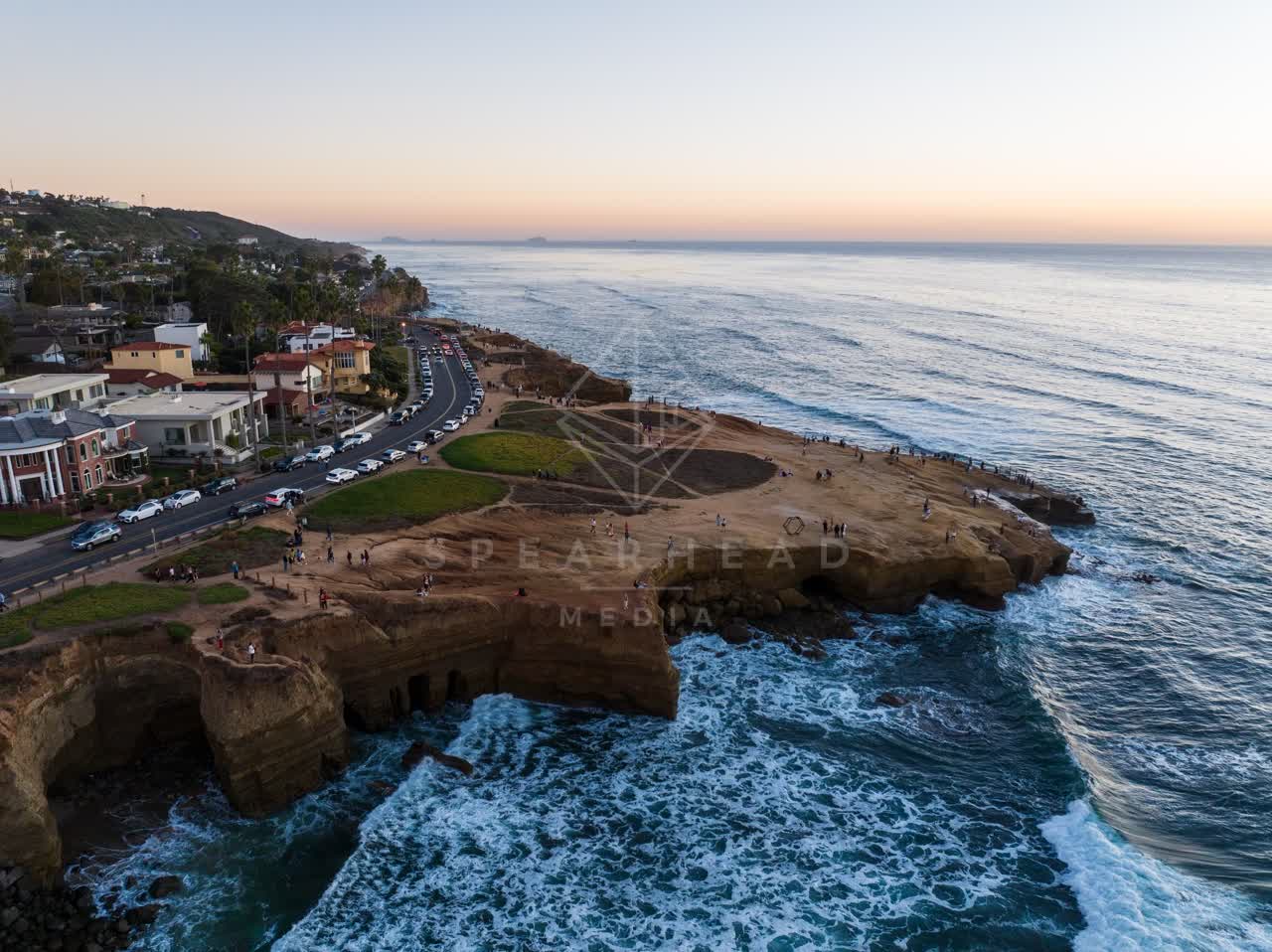 Aerial view of the cliffs, the surf and palm trees at Sunset Cliffs, with people walking.