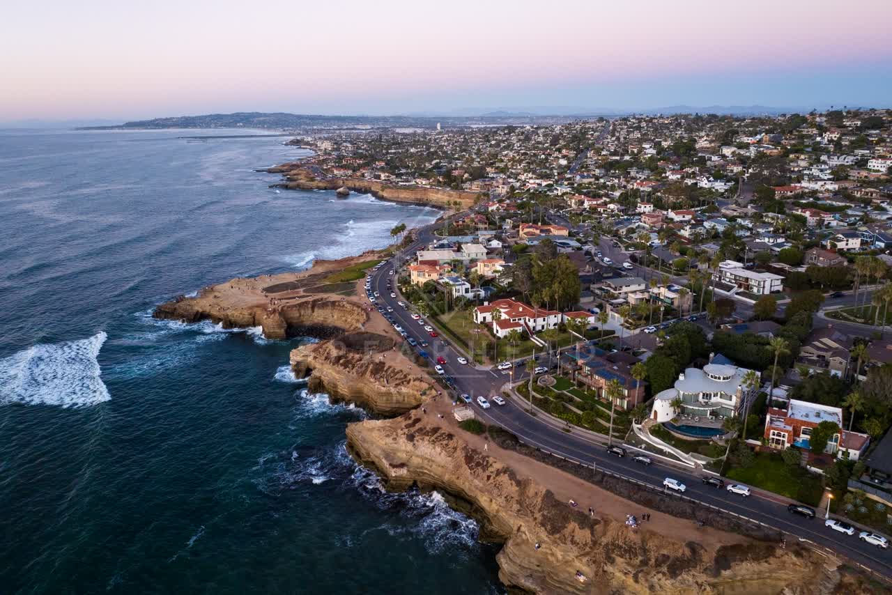 Aerial view of the cliffs, the surf and the ocean at Sunset Cliffs, with people walking.