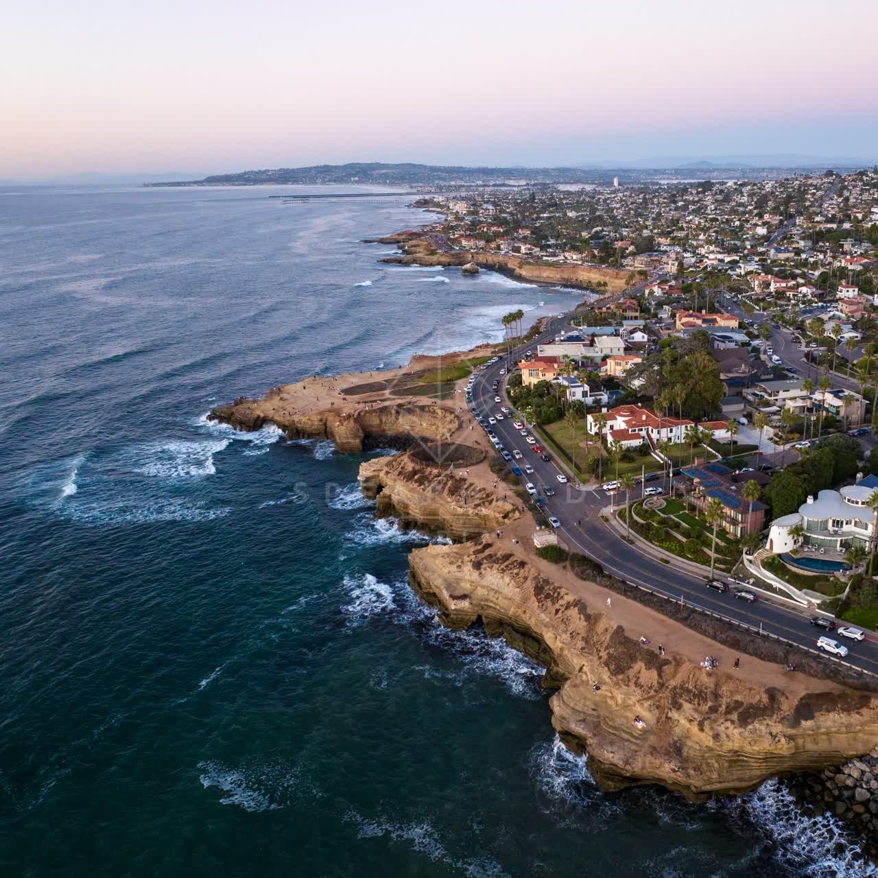 Aerial view of the cliffs, palm trees and the ocean at Sunset Cliffs, with people walking.