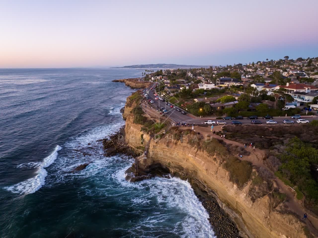 Aerial view of the cliffs, the surf and palm trees at Sunset Cliffs, with people walking.
