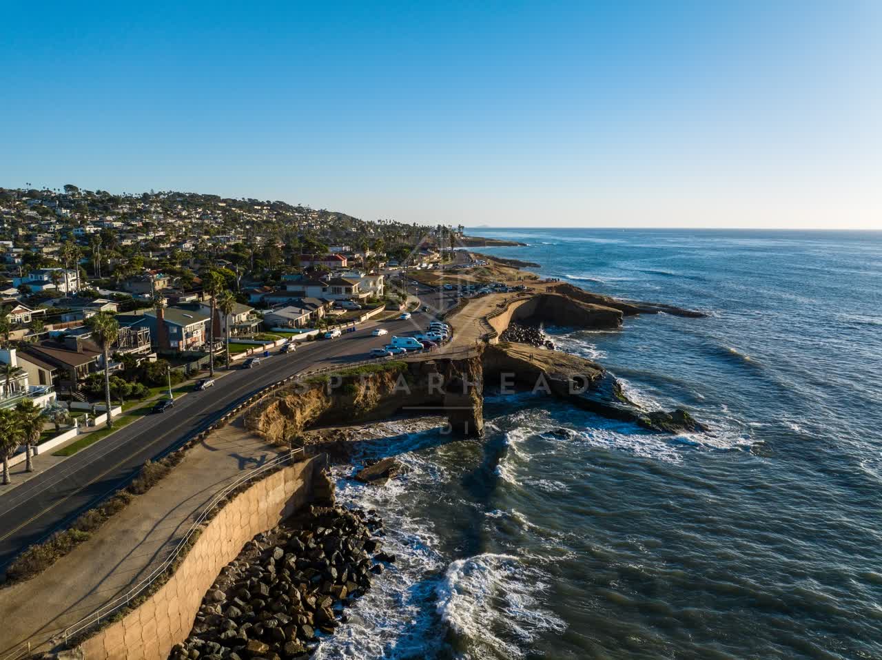 Aerial view of the cliffs, palm trees and the ocean at Sunset Cliffs, with people walking.