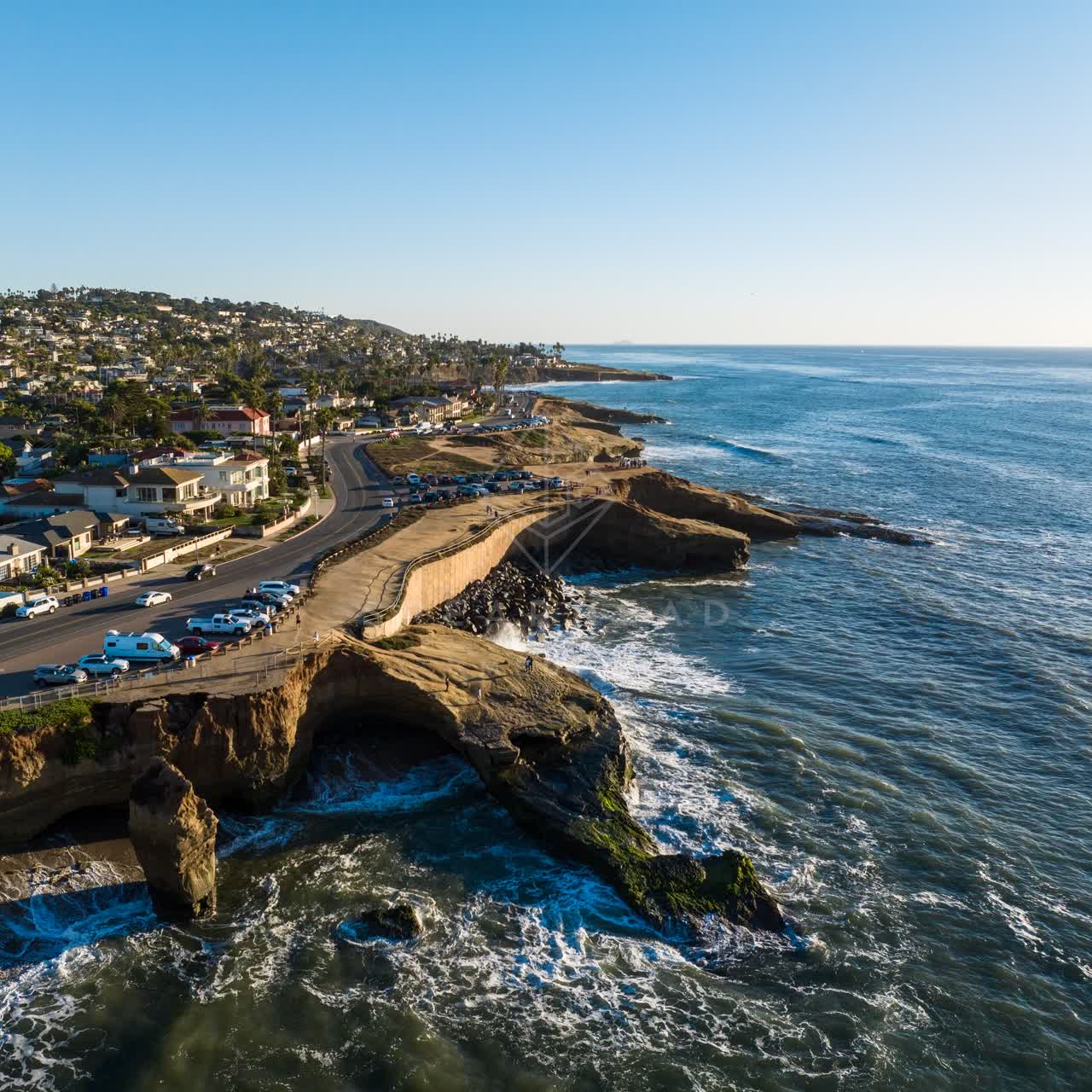 Aerial view of the cliffs, the surf and the ocean at Sunset Cliffs, with people walking.