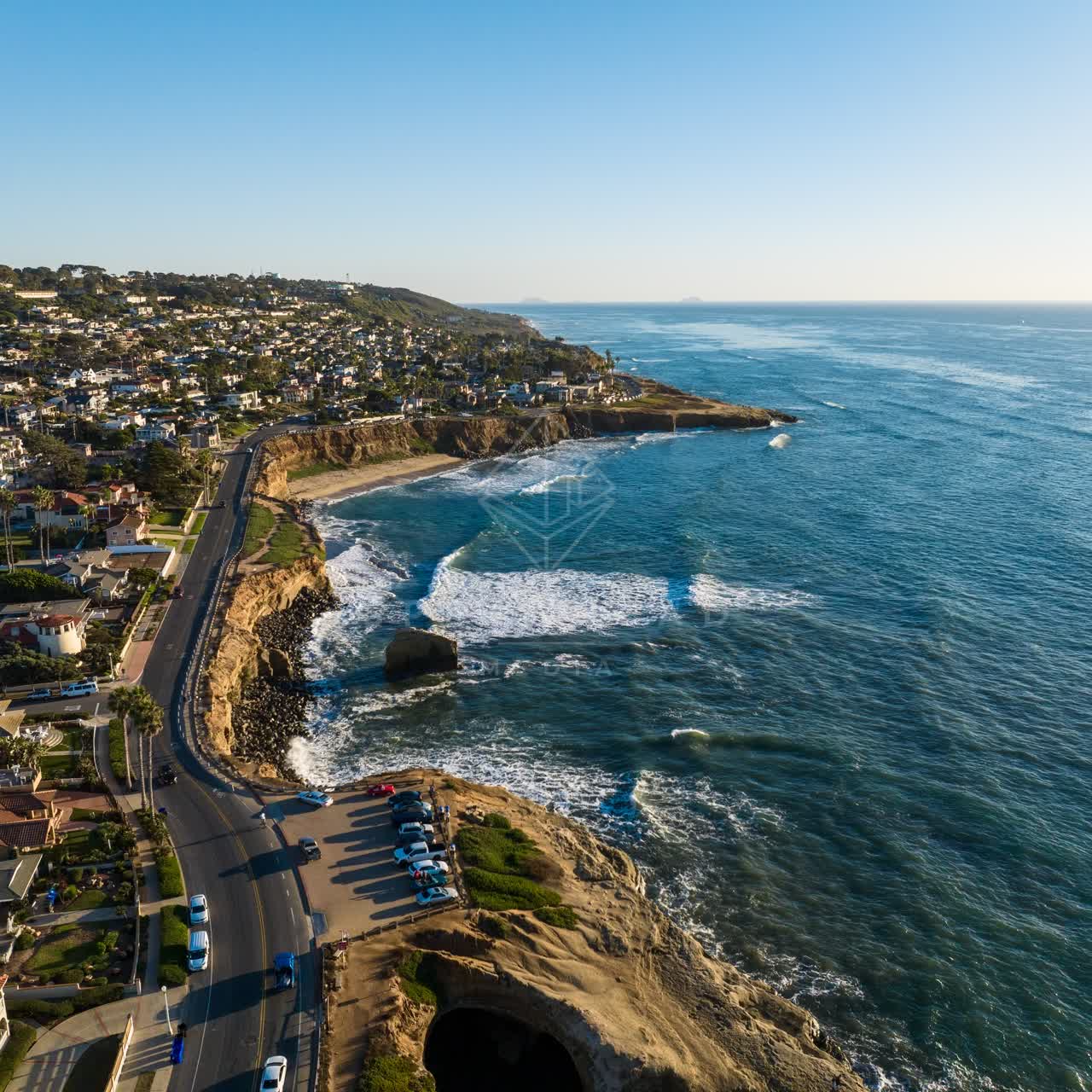 Aerial view of the cliffs, the surf and palm trees at Sunset Cliffs, with people walking.