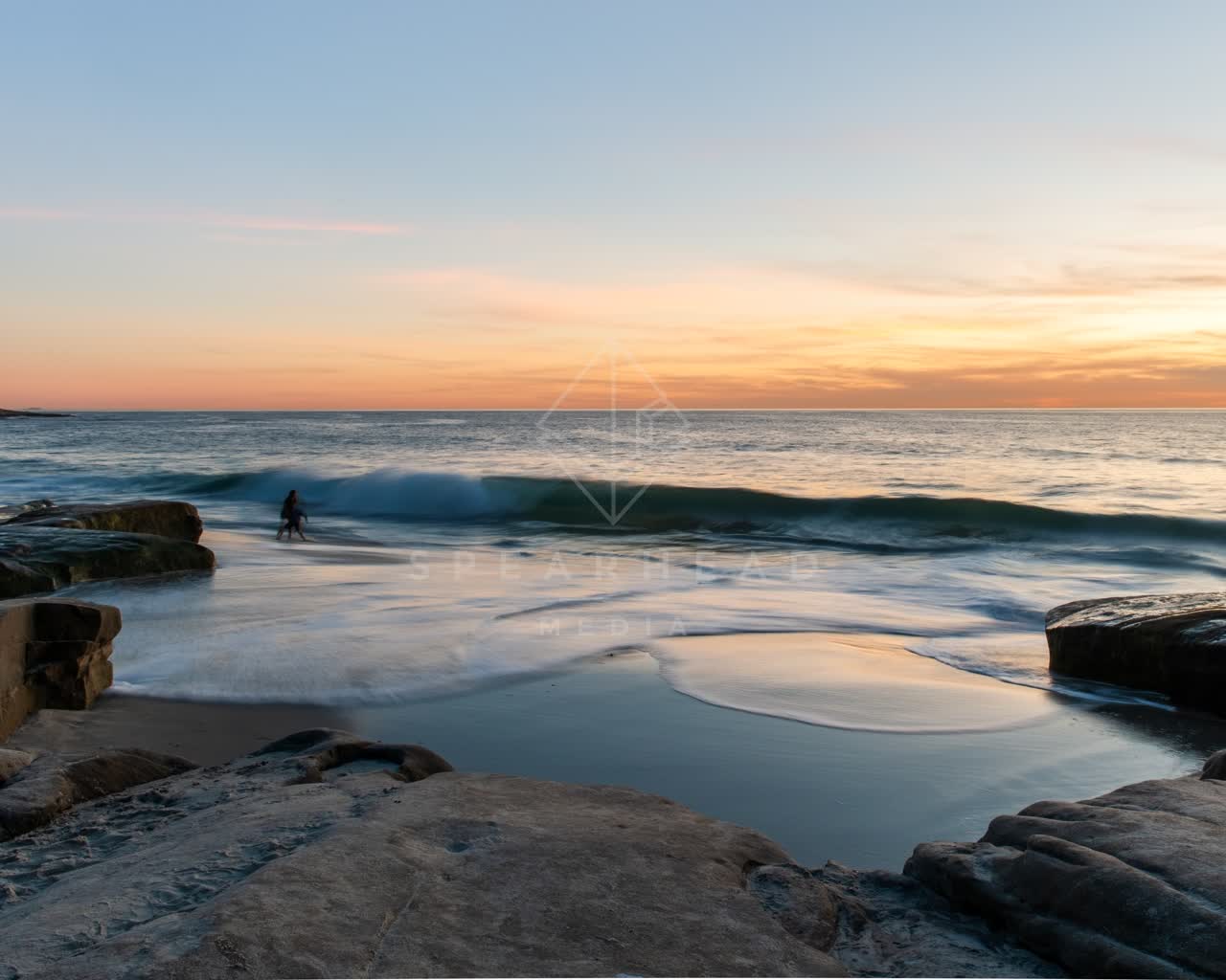 The beach, the surf and the ocean at Windansea, with people walking.