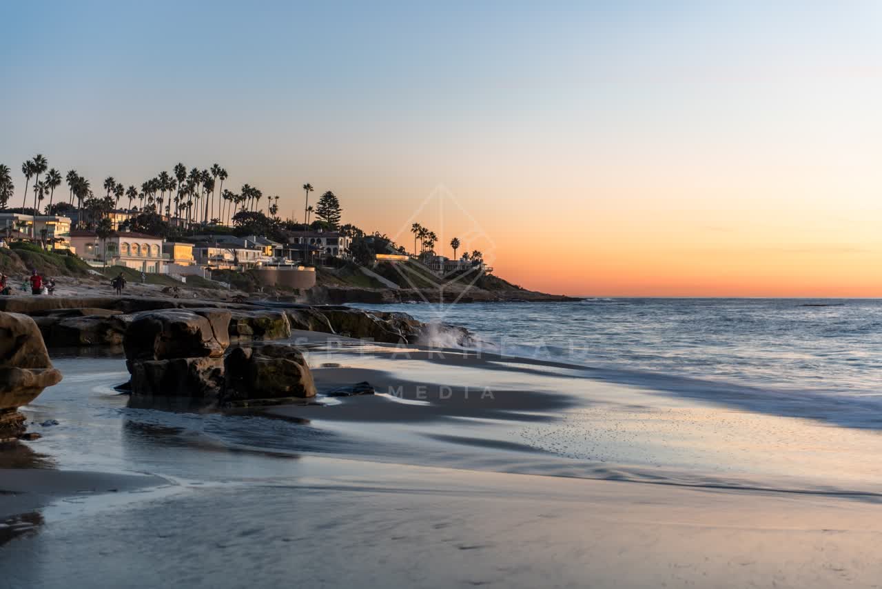 The beach, palm trees and the ocean at Windansea, with people walking.