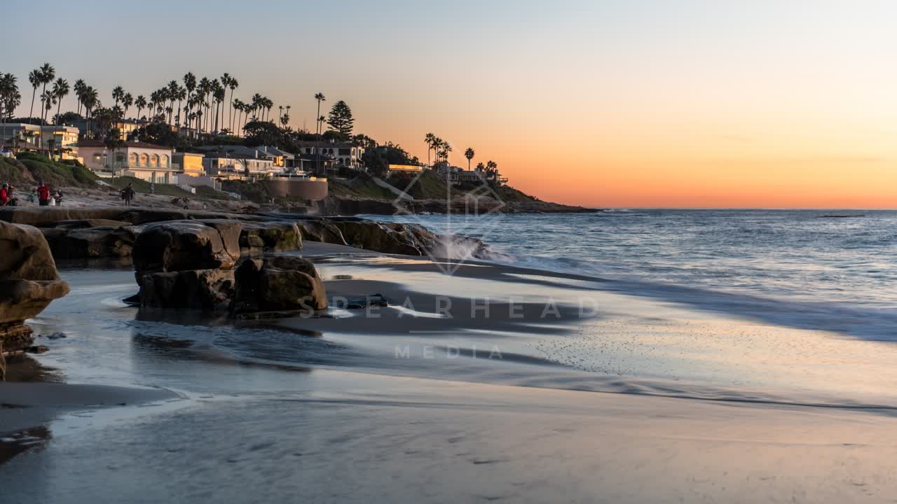 The beach, the surf and palm trees at Windansea, with people walking.