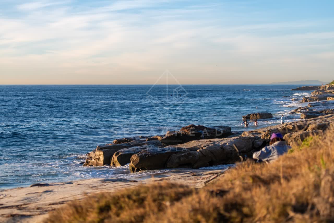 The beach, the surf and the ocean at Windansea, with people walking.