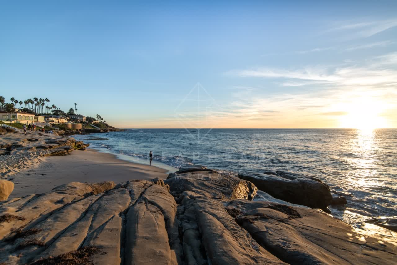 The beach, palm trees and the ocean at Windansea, with people walking.
