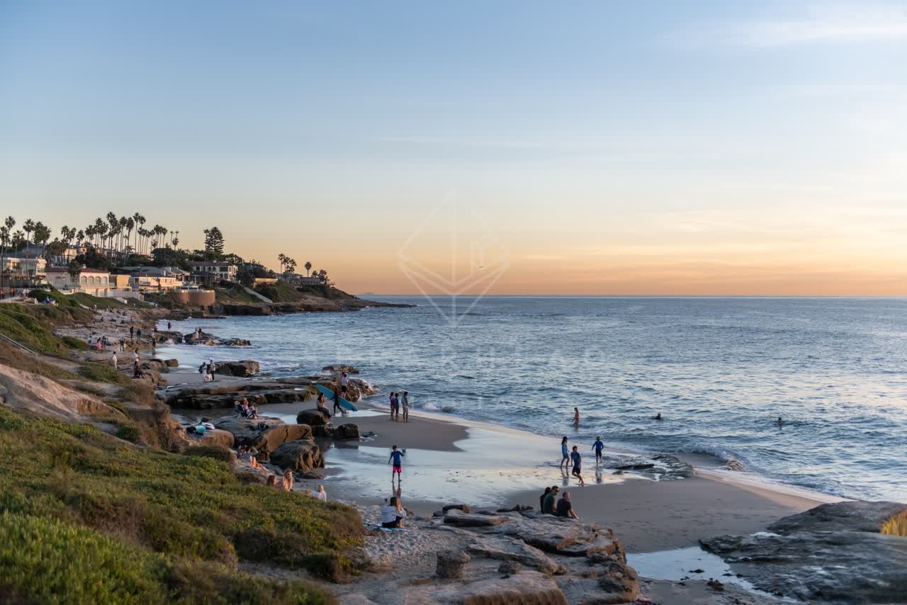 Elevated view of the beach, palm trees and the ocean at Windansea, with a crowd gathered.