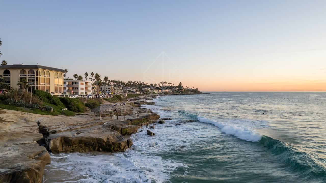 Low aerial view of the cliffs, the surf and palm trees at Windansea.
