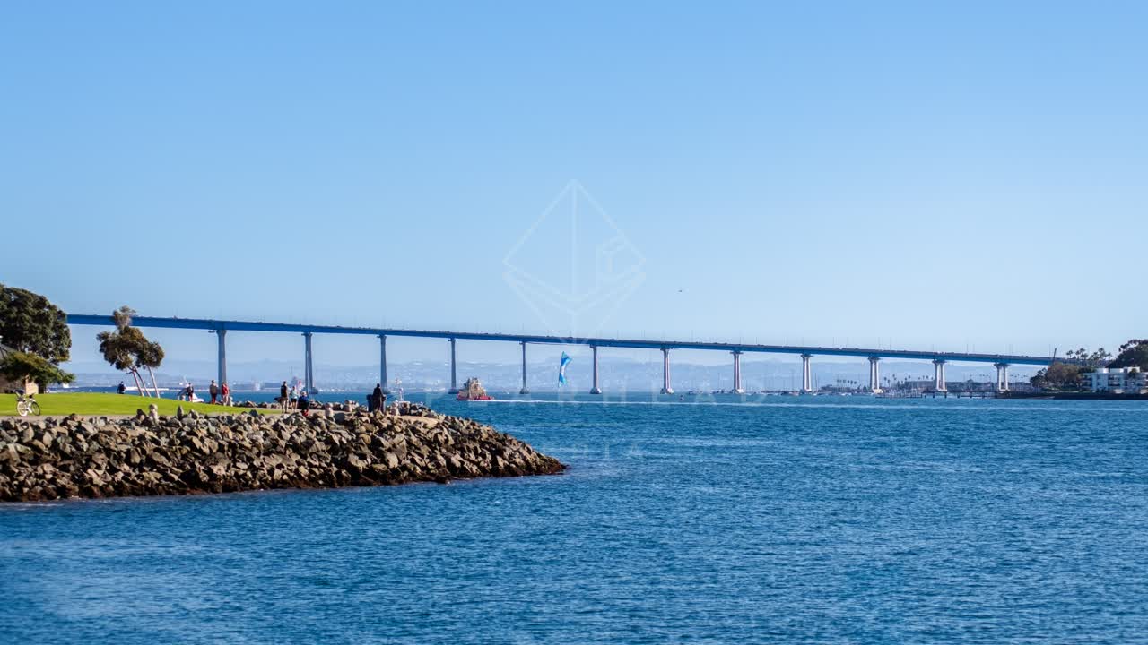 The harbor, the bridge and the skyline at Coronado Bridge, with people walking.