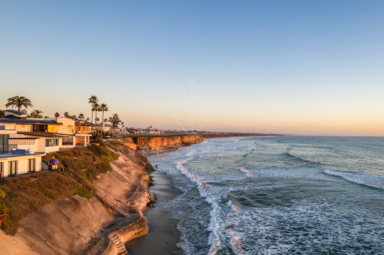 Aerial view of the cliffs, the surf and palm trees at Terramar Beach, with people walking.