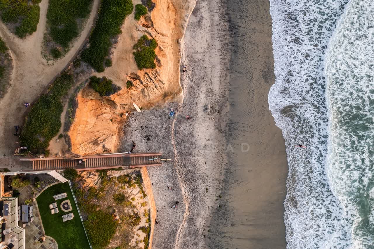 Aerial view of the cliffs, the surf and the ocean at Terramar Beach, with people walking.