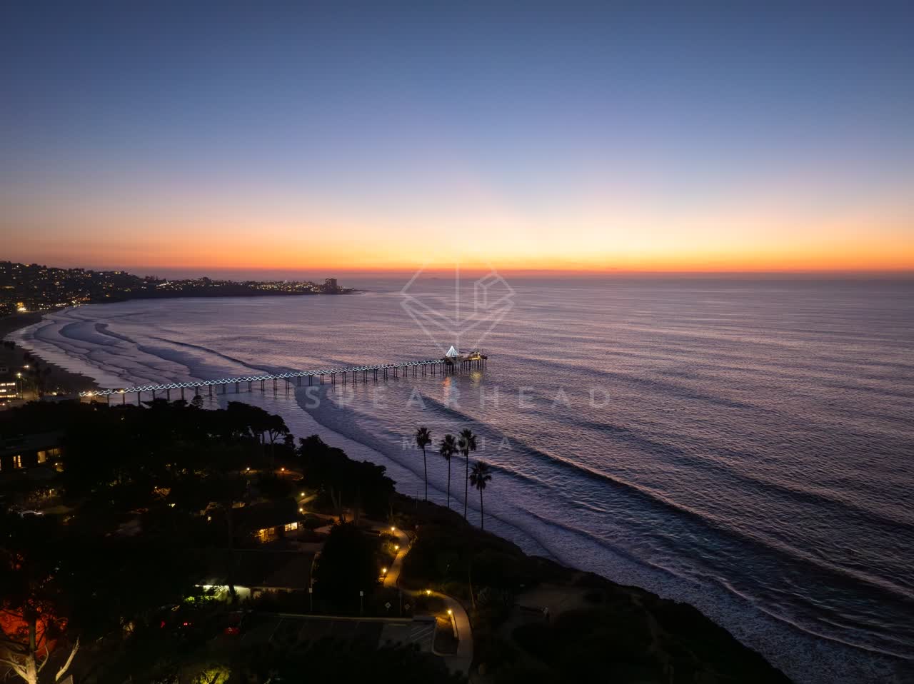 Aerial view of the cliffs, the pier and palm trees at La Jolla Shores.