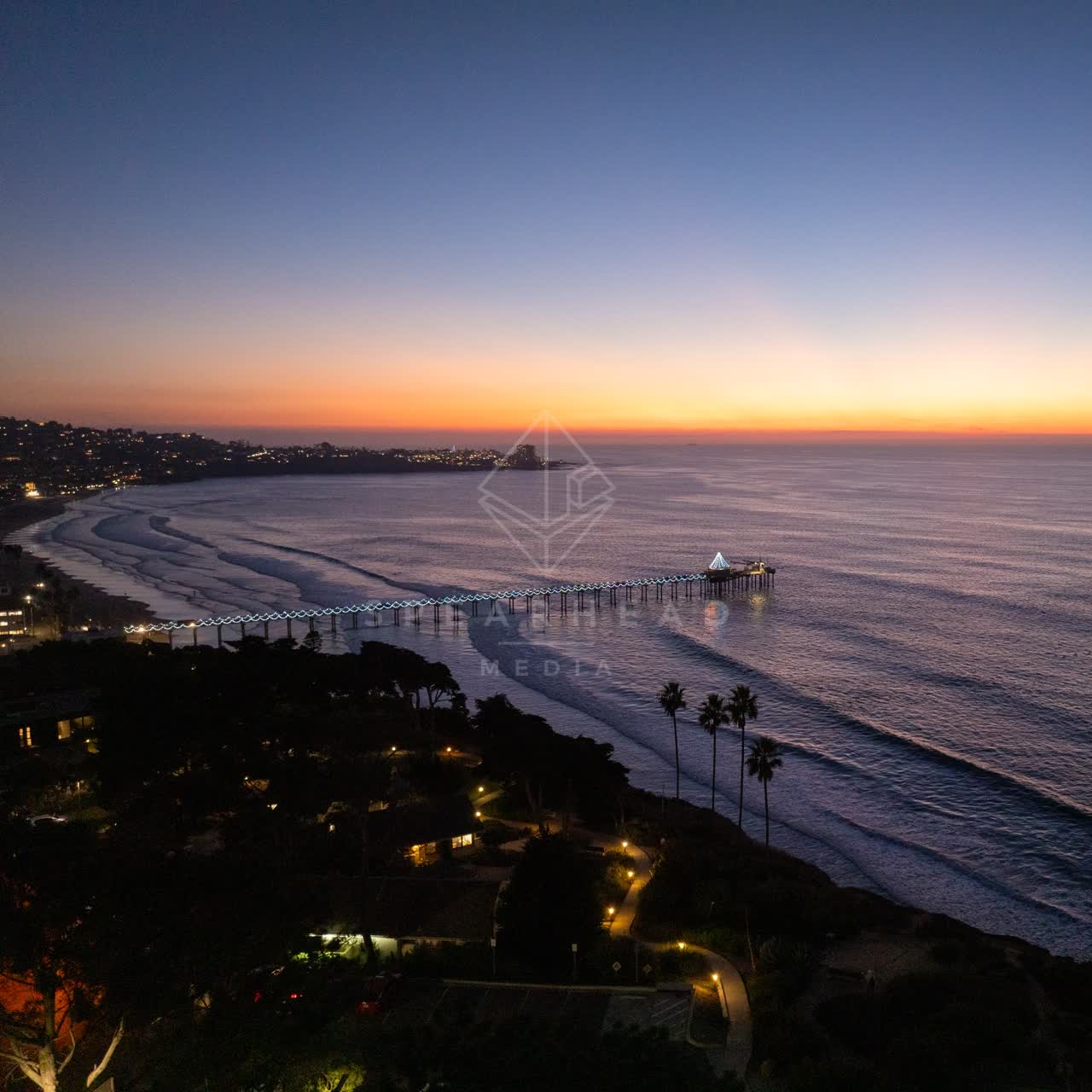 Aerial view of the cliffs, the pier and palm trees at La Jolla Shores.