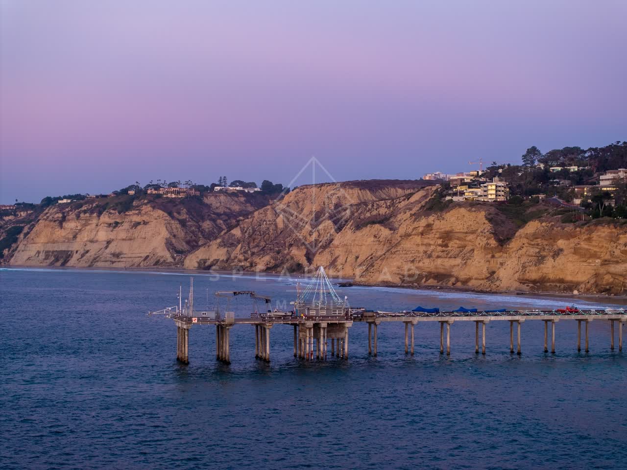 Low aerial view of the cliffs, the pier and the ocean at La Jolla Shores.
