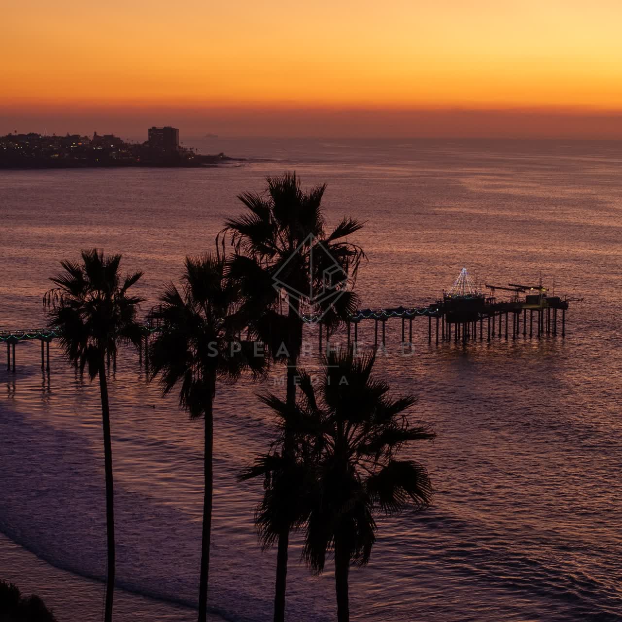 Low aerial view of the beach, the pier and the skyline at La Jolla Shores.