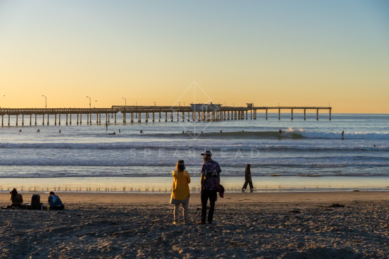 The beach, the surf and the pier in Ocean Beach, with people walking.